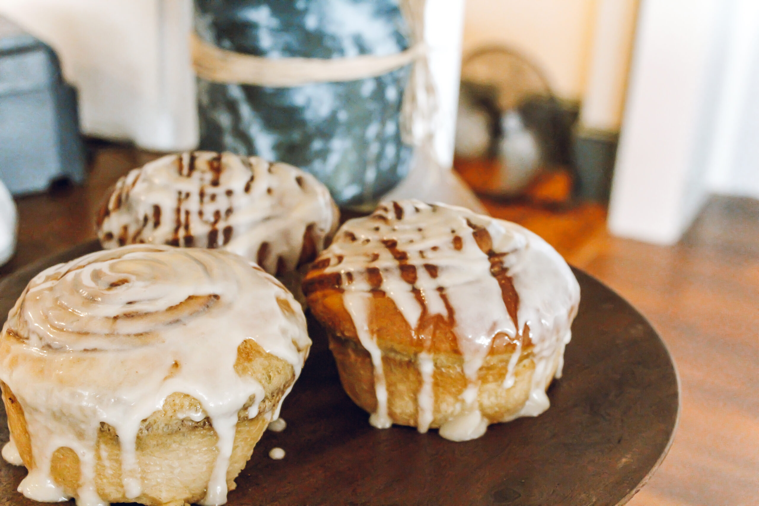 three glazed donuts sitting on a wooden plate