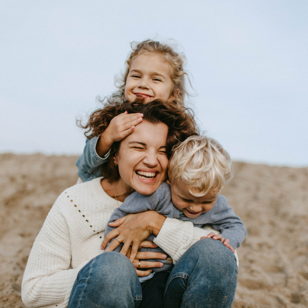 a woman and two children are sitting on the beach